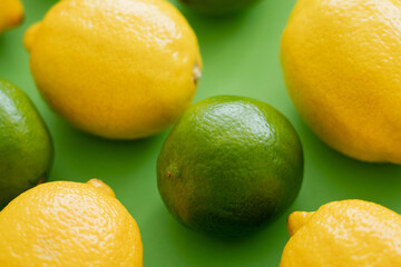 Close up view of ripe lime and lemons on green background