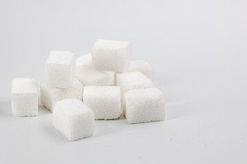 Many cubes of white ordinary sugar are piled in a pile on a light background close-up