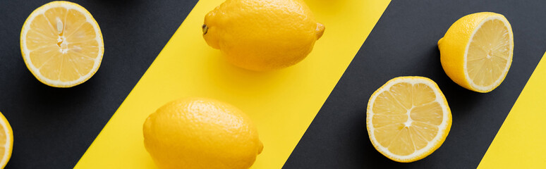 Flat lay with ripe lemons on black and yellow background, banner