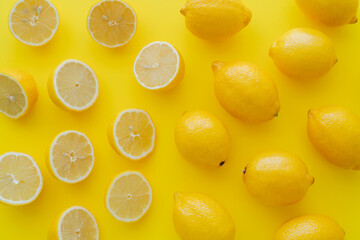 Flat lay with halves and whole lemons on yellow surface