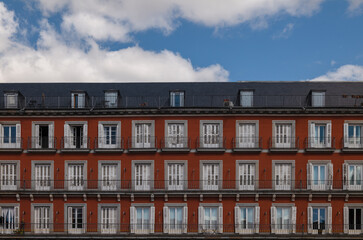 Facade of red building with balconies against cloudy sky. Madrid, Spain