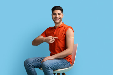 Immunization Campaign. Smiling Middle Eastern Guy Pointing At Adhesive Band On Shoulder
