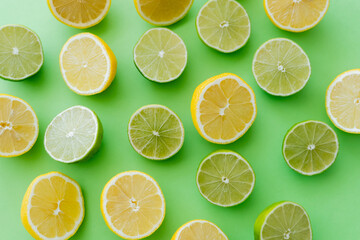 Fototapeta premium Top view of cut limes and lemons on green background