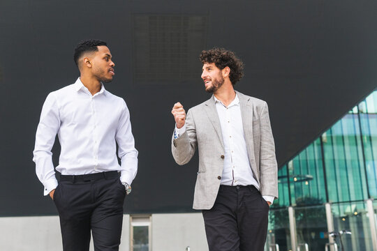 Positive multiethnic businessmen standing near office building
