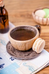Ceramic cup with tea and macaron on a wooden table, copy space