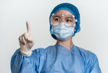 Female doctor or nurse wearing protective suit is pointing the blank above  with single finger 