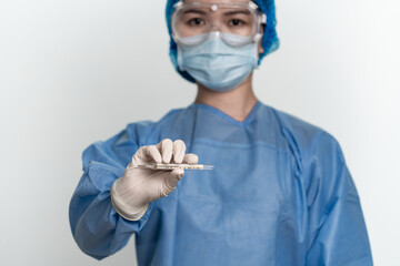 Female doctor or nurse wearing protective suit is holding a thermometer