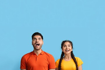 Amazed Young Middle Eastern Couple Looking Up At Copy Space With Excitement