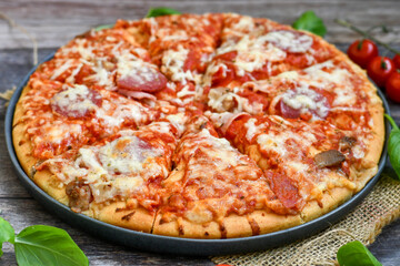  Close up of   classic  Italian Pizza   with Ham and salami . Fresh basil,tomato sauce ,mozzarella cheese , mushrooms and  green peppers