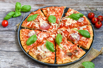  Close up of   classic  Italian Pizza   with Ham and salami . Fresh basil,tomato sauce ,mozzarella cheese , mushrooms and  green peppers