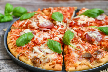  Close up of   classic  Italian Pizza   with Ham and salami . Fresh basil,tomato sauce ,mozzarella cheese , mushrooms and  green peppers