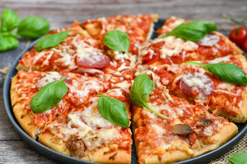  Close up of   classic  Italian Pizza   with Ham and salami . Fresh basil,tomato sauce ,mozzarella cheese , mushrooms and  green peppers