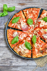  Close up of   classic  Italian Pizza   with Ham and salami . Fresh basil,tomato sauce ,mozzarella cheese , mushrooms and  green peppers