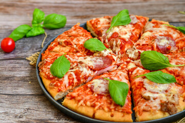  Close up of   classic  Italian Pizza   with Ham and salami . Fresh basil,tomato sauce ,mozzarella cheese , mushrooms and  green peppers