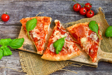  Close up of   classic  Italian Pizza   with Ham and salami . Fresh basil,tomato sauce ,mozzarella cheese , mushrooms and  green peppers