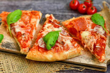  Close up of   classic  Italian Pizza   with Ham and salami . Fresh basil,tomato sauce ,mozzarella cheese , mushrooms and  green peppers