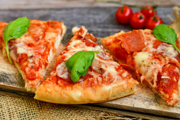  Close up of   classic  Italian Pizza   with Ham and salami . Fresh basil,tomato sauce ,mozzarella cheese , mushrooms and  green peppers