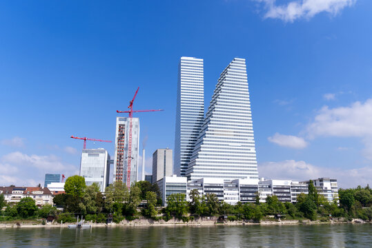 Roche towers at City of Basel with Rhine River in the foreground on a blue cloudy spring day. Photo taken April 27th, 2022, Basel, Switzerland.