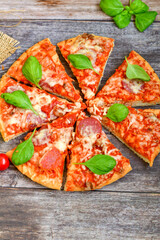  Close up of   classic  Italian Pizza   with Ham and salami . Fresh basil,tomato sauce ,mozzarella cheese , mushrooms and  green peppers