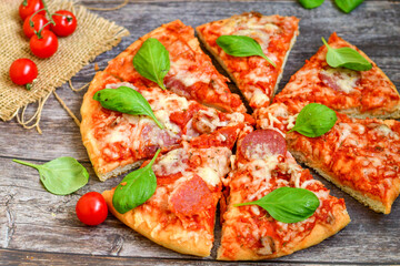  Close up of   classic  Italian Pizza   with Ham and salami . Fresh basil,tomato sauce ,mozzarella cheese , mushrooms and  green peppers