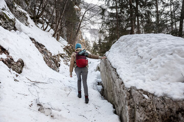 Hiker in uphill icy mountain trail wearing crampons on hiking boots.