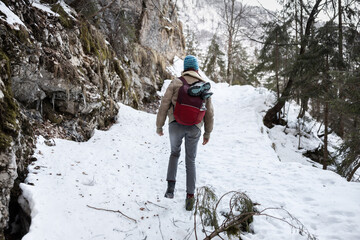 Hiker in uphill icy mountain trail wearing crampons on hiking boots.
