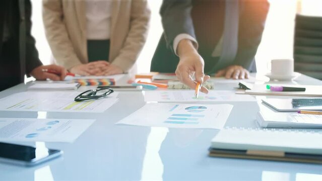 Diverse Group Of Young Businesspeople Discussing Brainstorming Ideas. Financial Data And Charts, Tech Devices. Hand Close Up. Boardroom Meeting. Daylight