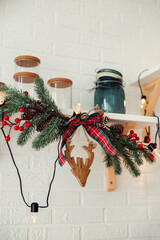 Christmas decor in the form of fir branches and a deer on the kitchen shelf.