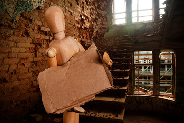 wooden puppet with a poster against the background of a destroyed building