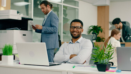 Fototapeta premium A very handsome young black man is in an aesthetic office as he sits back in his chair crosses his arms and smiles widely