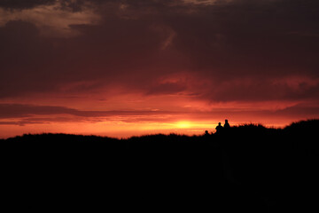 Silhouette of people standing on top of the dunes at sunset. High quality photo