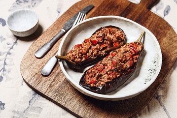 Imam bayildi. Traditional delicious Turkish food: halves of baked eggplant stuffed with vegetables on a plate. Selective focus