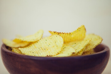 Potato chips in bowl on a wooden background. Fast food. Crispy potato on table wooden background. American tradition.