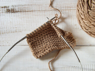 Knitting project in progress, stockinette stitch is applied. Brown cotton yarn and circular...