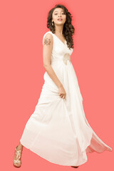 Beautiful Indian girl or female model wearing a white gown on a solid pink background