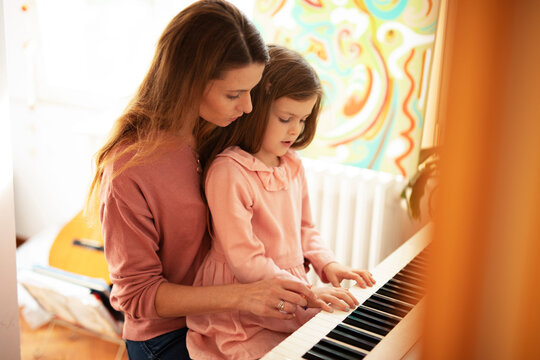Woman and girl playing a piano. Beautiful woman teaching a little girl playing a piano.