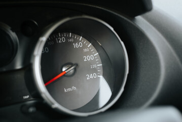 Close-up of car speedometer with red arrow and dial. Side view dashboard