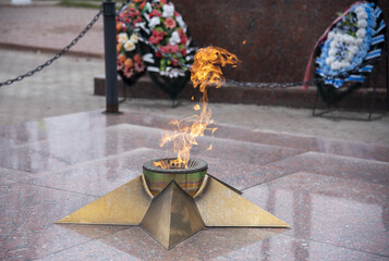 Eternal flame in the shape of a star in a provincial town. - obrazy, fototapety, plakaty