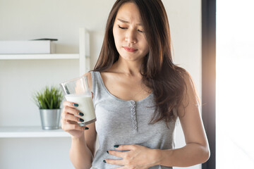 lactose intolerance concept. Woman holding a glass of milk and having a stomachache.