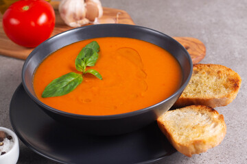 Fresh, healthy tomato soup with basil, pepper, garlic, tomatoes and bread on wooden background. Spanish gazpacho soup. Lentils and pumpkin soup.