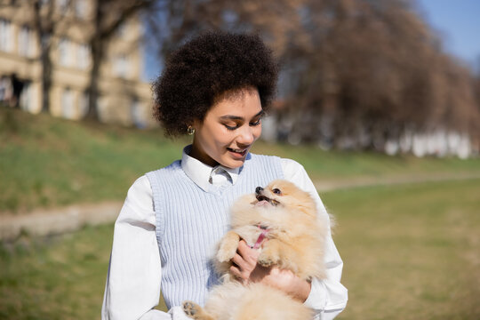 Positive African American Woman Holding In Arms Pomeranian Dog