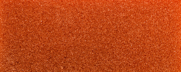 Orange porous sponge surface. Rough background