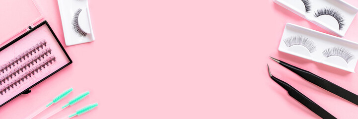 Tools for eyelash extension on trendy pastel pink background. False eyelashes, tweezers and...