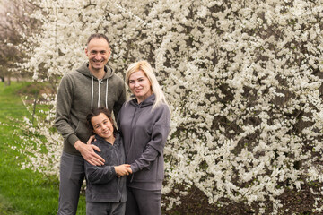 family having fun with flowering tree in blooming spring garden