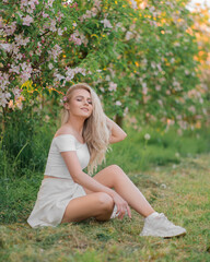 Naklejka na ściany i meble gentle, beautiful girl in white clothes among the apple orchard. Apple tree flowers