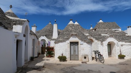 Fototapeta na wymiar Trullo / trulli dans la ville d’Alberobello, petites maisons blanches traditionnelles à toit conique dans la vallée d'Itria, province de Bari, dans les Pouilles / Puglia (Italie)