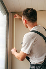 Young man applying mounting tape before sealing a window