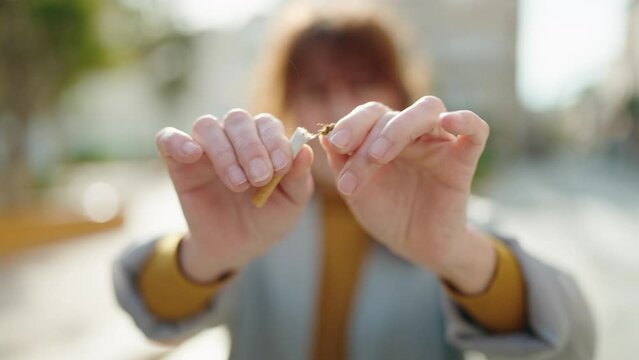 Middle age woman business worker breaking cigarette at park
