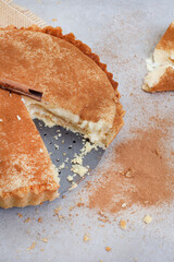 Traditional South African milk tart freshly baked and in tin. Mottled grey and rustic surface with copy space