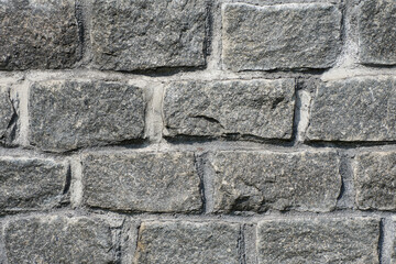 Natural granite stone wall. Rough natural stones. Background of a stone wall cladding texture gray stone bricks.